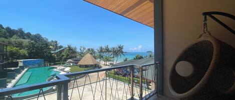 Un balcón con vistas a una piscina y a la playa.