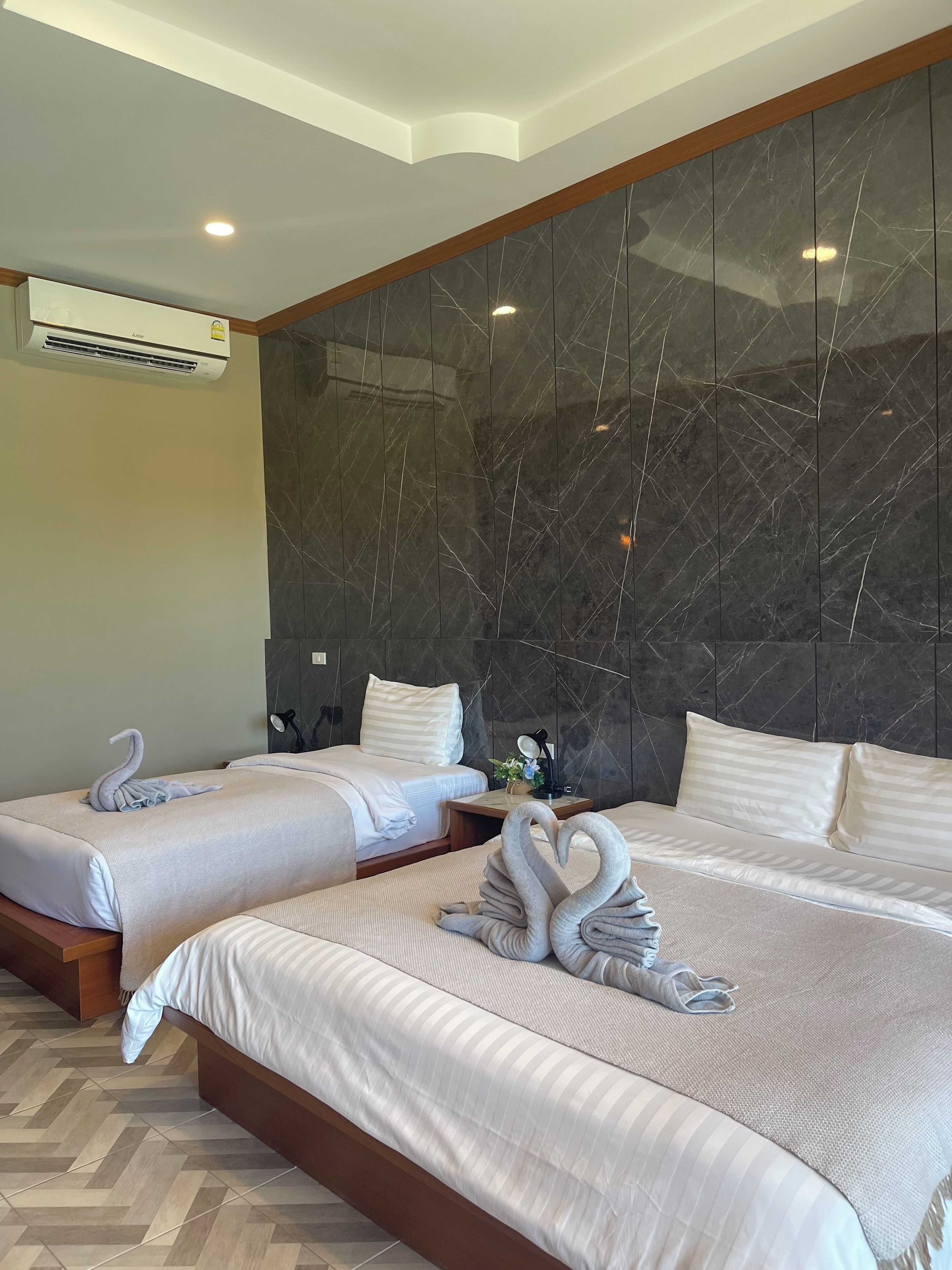A hotel room with two beds, marble walls, and a modern air conditioning unit.