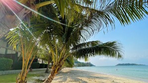 A beach with palm trees, clear water, and a distant island. - Kaibae Beach Resort (Ko Chang)