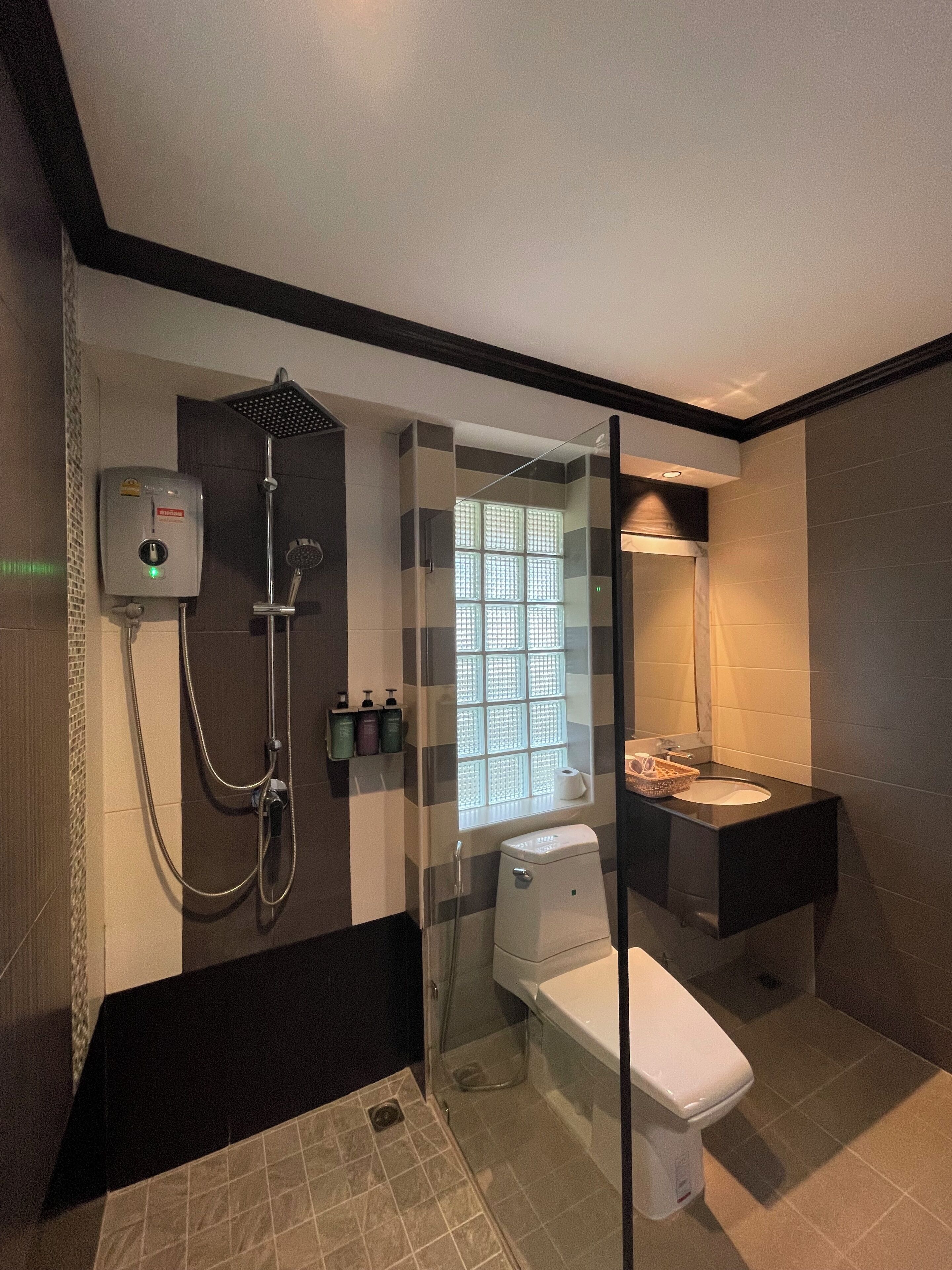 A modern bathroom with a glass-enclosed shower, a toilet, and a sink with a mirror.