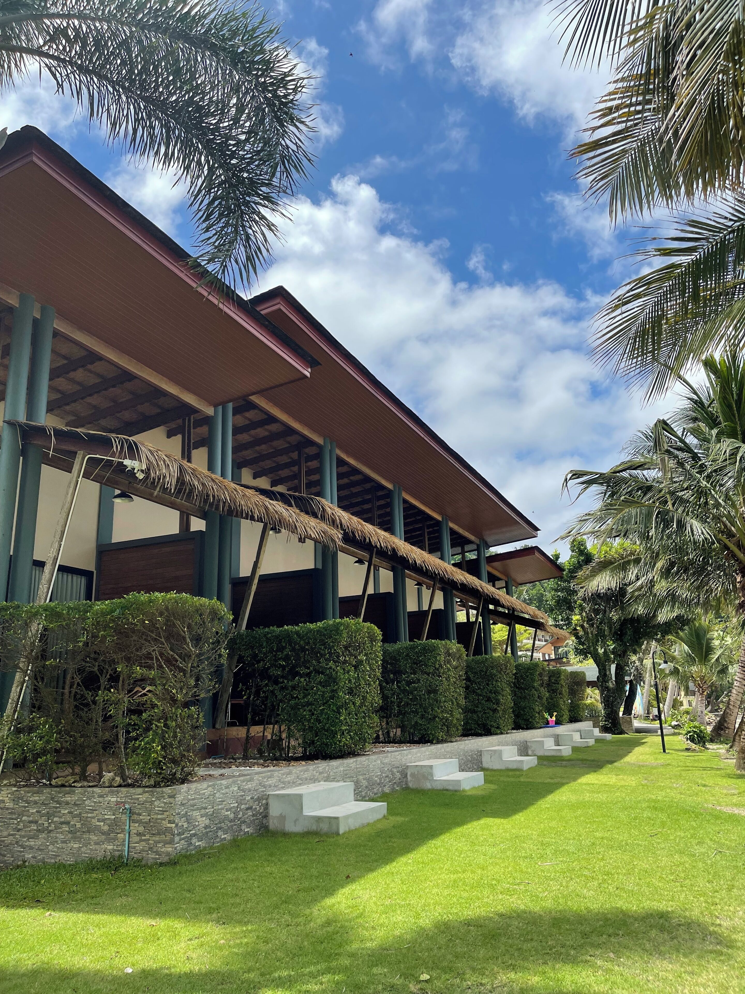 A building with a covered patio area, stone steps, and well-maintained greenery.