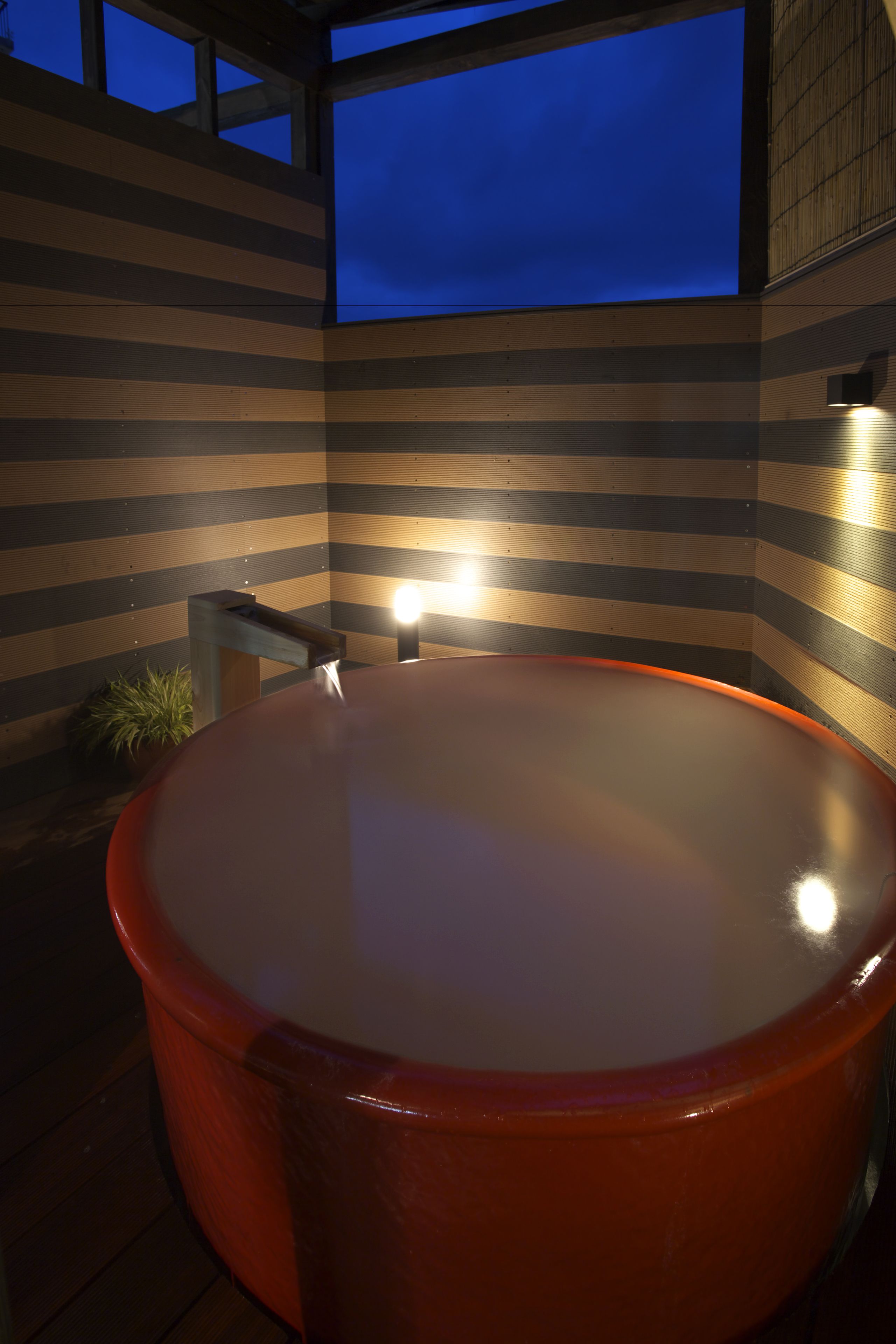 Ein Whirlpool mit einer Holzlamellenwand und einem Fenster.