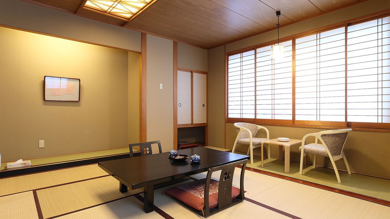 Um quarto japonês tradicional com tatames, uma mesa baixa com um conjunto de chá e portas deslizantes.