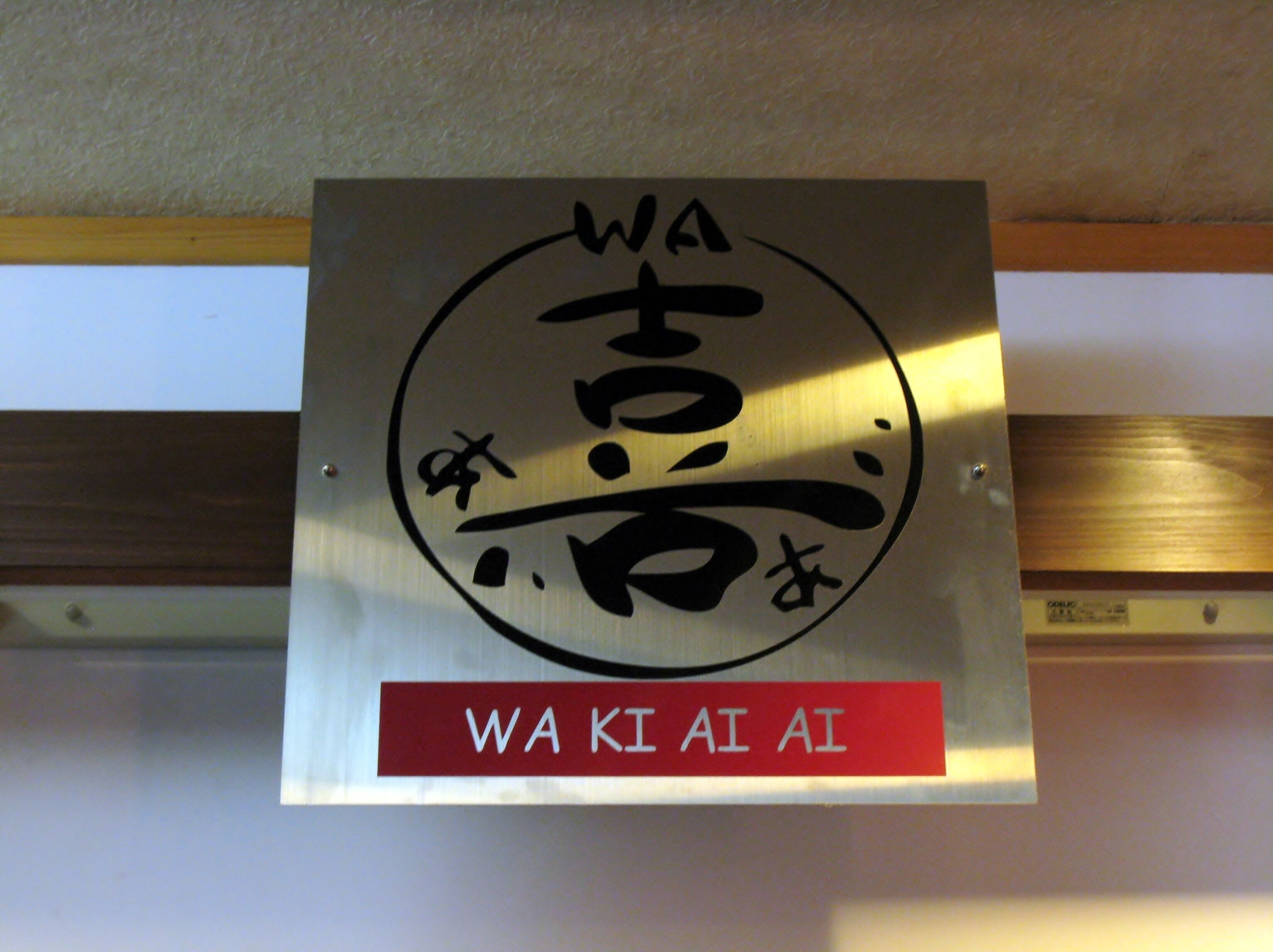 A sign with Japanese characters and the English translation "WA KI AI AI" on a wall.