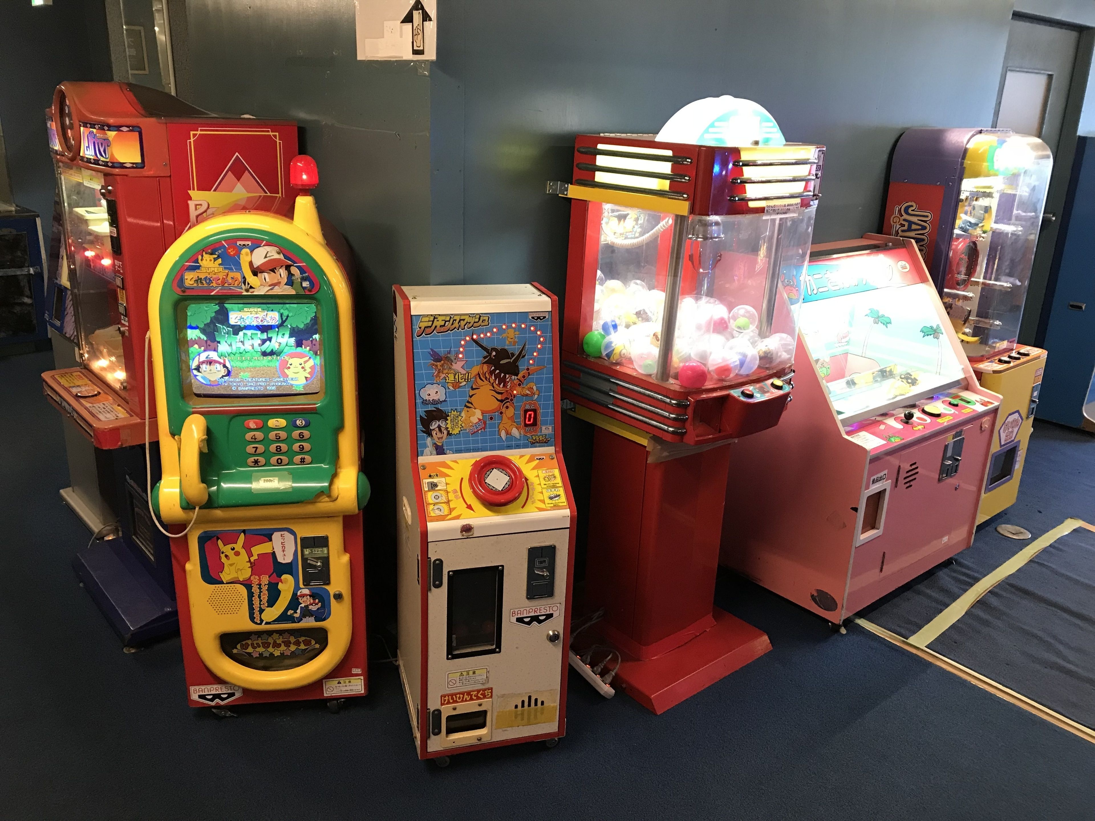 A row of arcade machines in a room with a blue carpet.