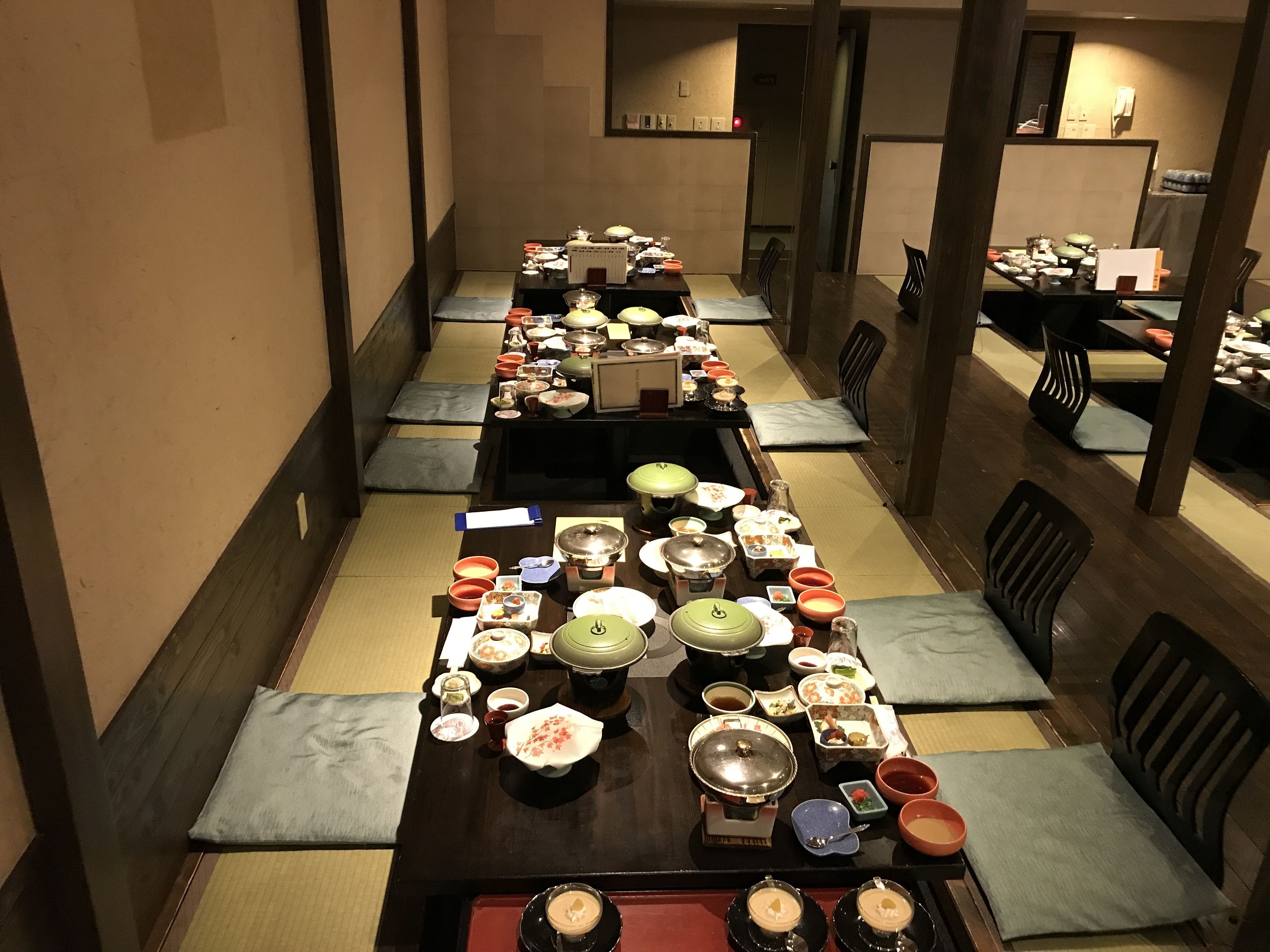 A traditional Japanese dining room with tatami mats, low tables, and a variety of dishes and utensils.