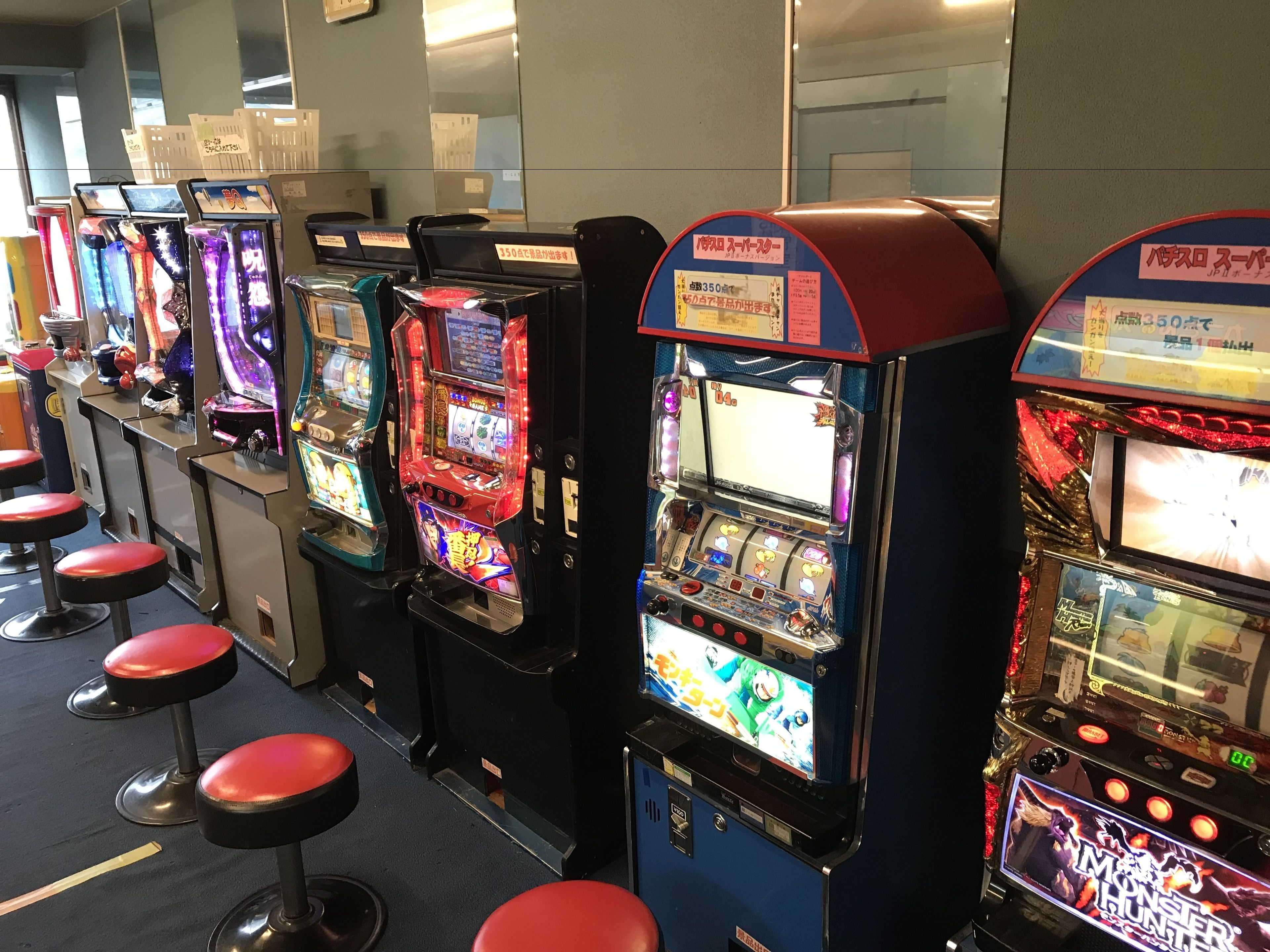 A row of slot machines with red stools in front.