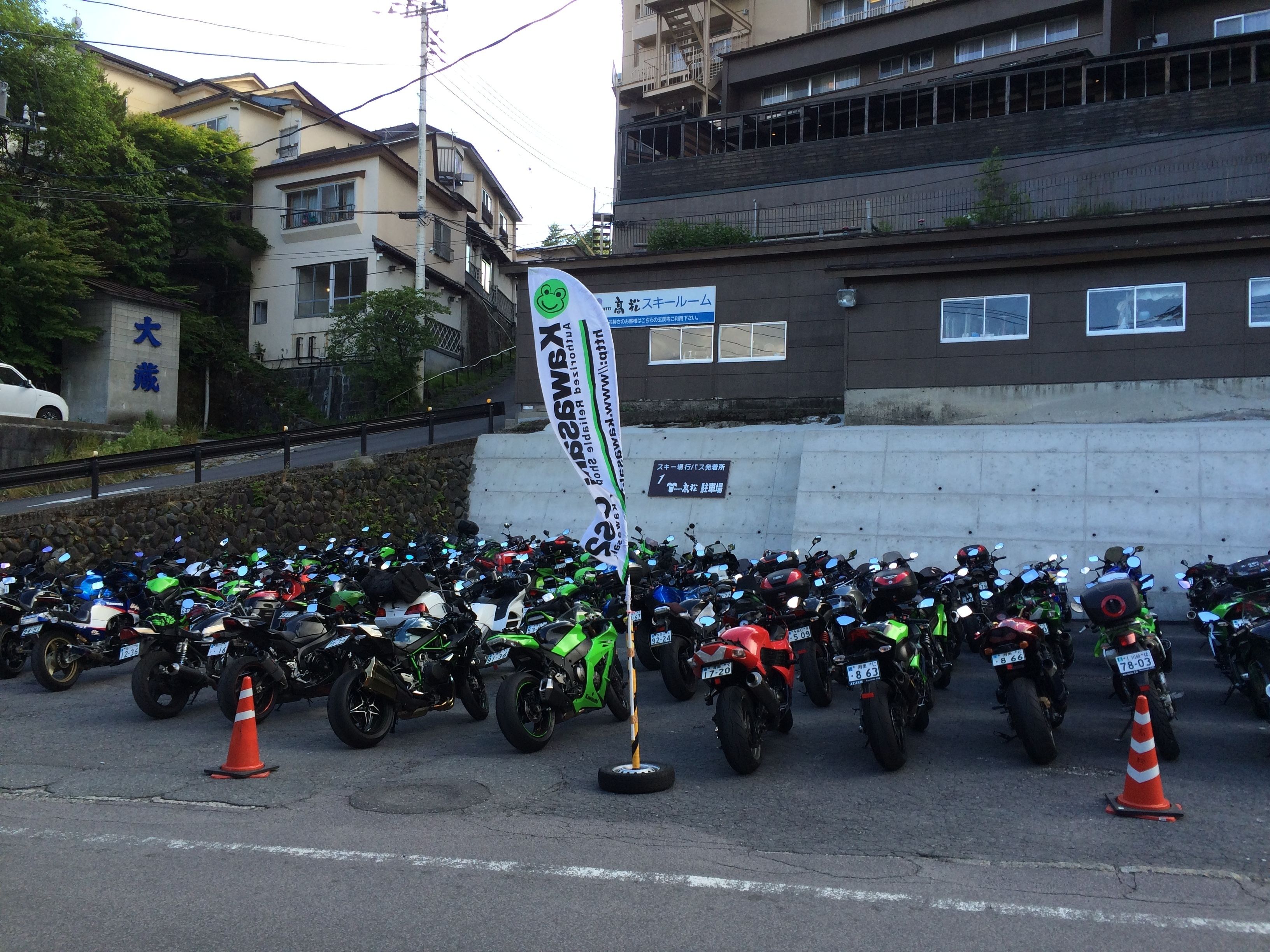 A row of motorcycles parked on a street with buildings in the background.