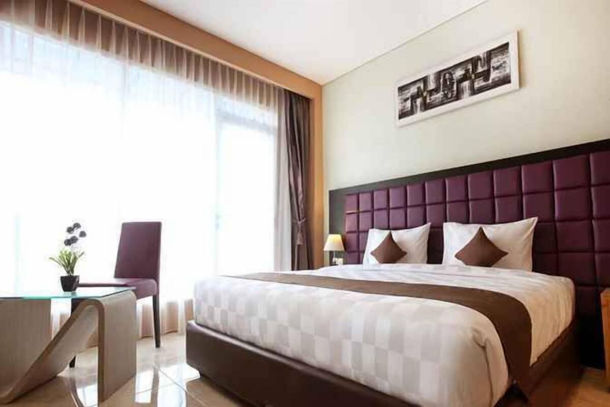 A hotel room with a large bed, a desk, and a chair.