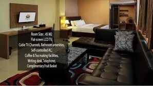 A hotel room with a flat-screen LCD TV, cable TV channels, bathroom amenities, self-controlled AC, coffee & tea making facilities, a writing desk, telephone, and a complimentary fruit basket.