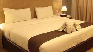 A hotel room with a large bed, a nightstand, a lamp, and a window with curtains.