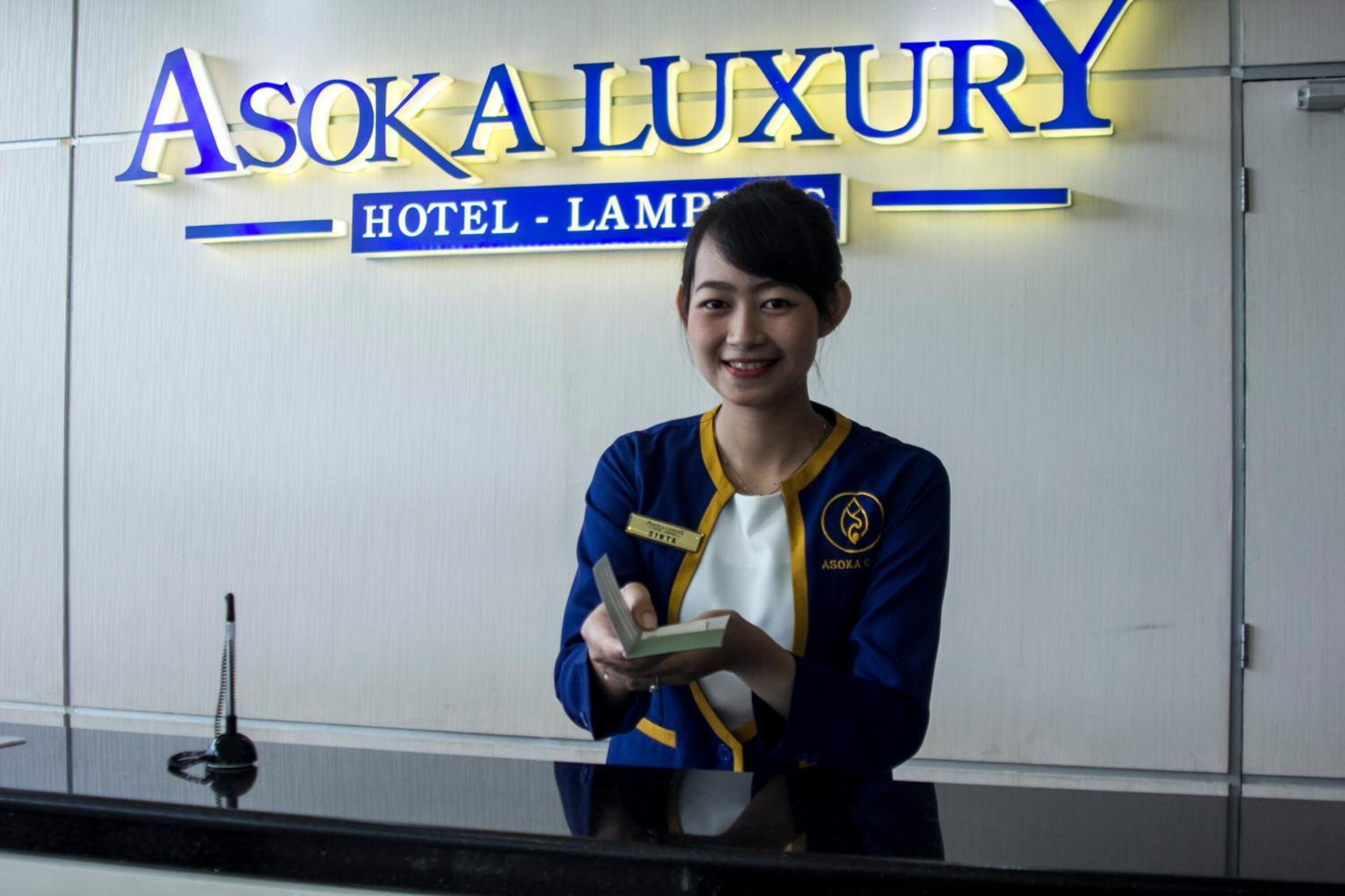 Una mesa de recepción de hotel con un cartel que dice "Asoka Luxury Hotel - Lampang".