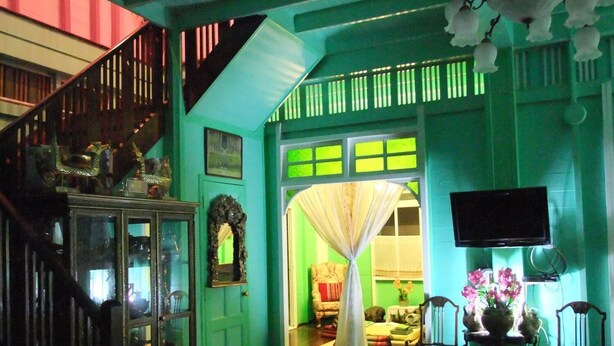 A room with a staircase, a green door, a television, and a chair. - Panida Suite (Bangkok)