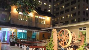 A courtyard with a wooden bench, potted plants, and a large wooden wheel structure. - Panida Suite (Bangkok)