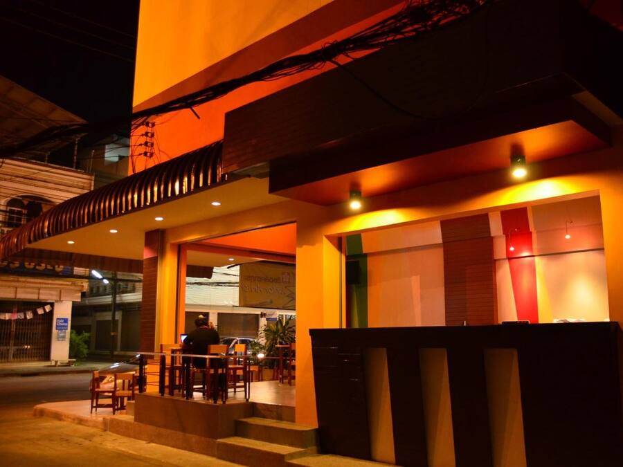An exterior of a building with a brightly lit entrance and outdoor seating area.
