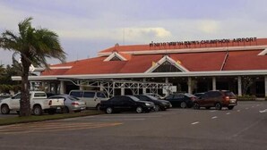 En byggnad med ett rött tak och texten ”CHIMPSON AIRPORT” på fasaden. Det står bilar parkerade framför byggnaden.