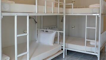 A bunk bed room with a white color scheme, a small shelf, and a door.