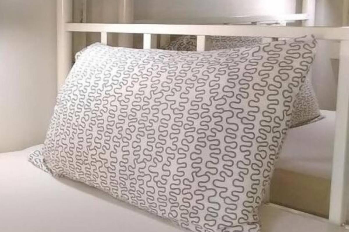 A white crib with a patterned pillow.