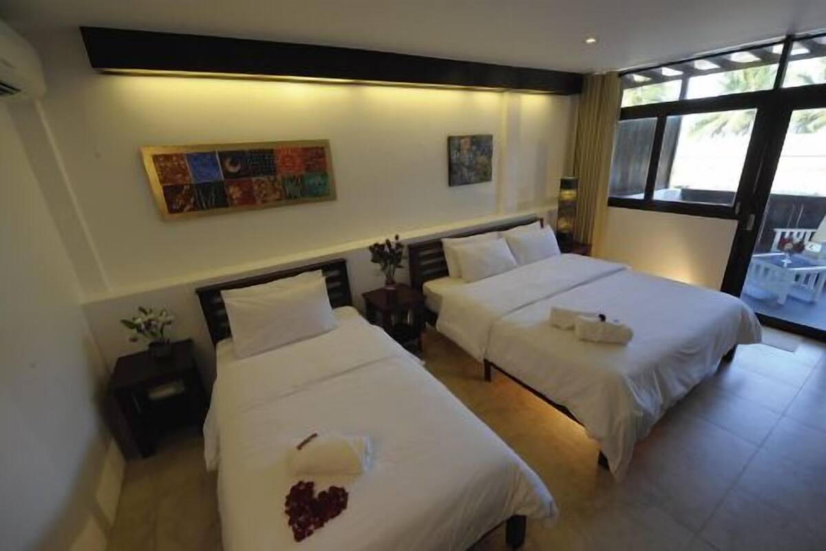 Habitación de hotel con dos camas, una mesita de noche, una obra de arte en la pared y una ventana con vistas.