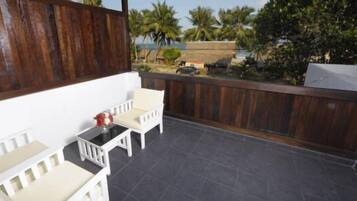 A balcony with a white chair, a small table, and a grill.