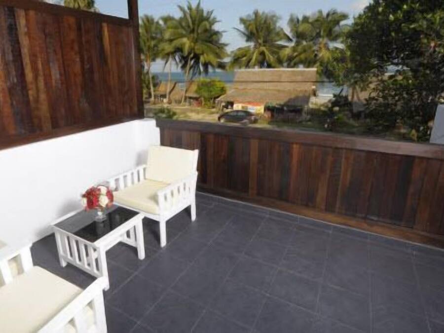 A balcony with a white chair, a small table, and a grill.