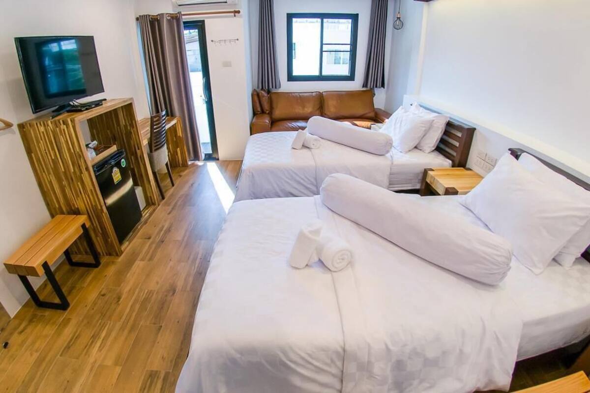 Habitación de hotel con dos camas, un televisor, un escritorio de madera y una ventana.