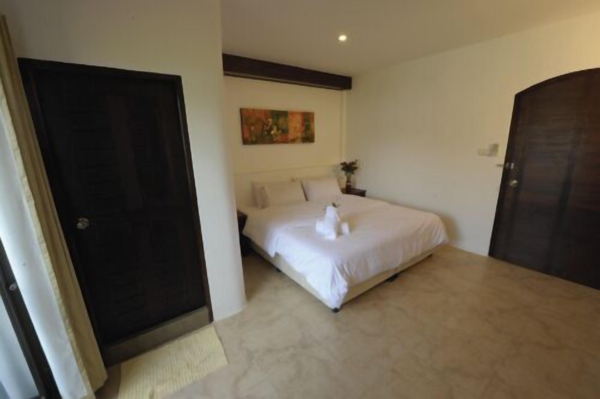 A hotel room with a bed, a painting on the wall, and a door.