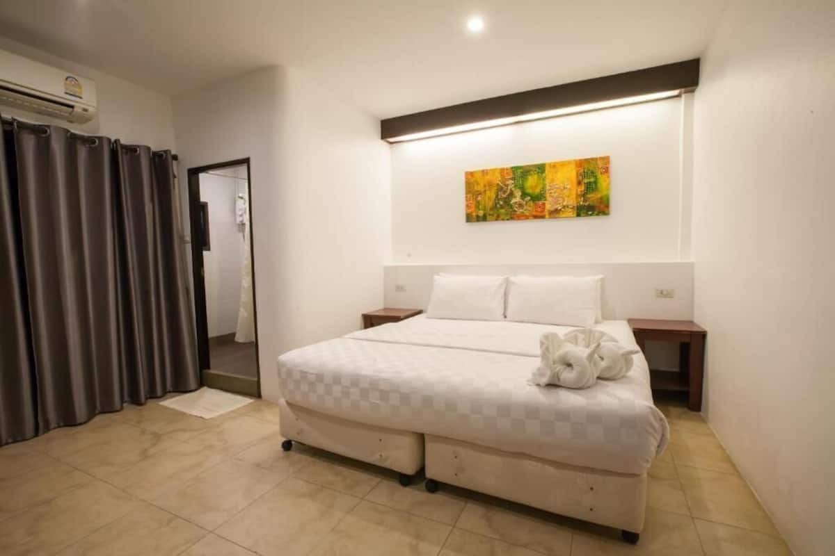 Un dormitorio con una cama, un cuadro en la pared, una cortina y una puerta.