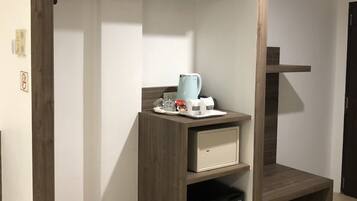 Una habitación compacta con armario empotrado, una pequeña kitchenette y un cubo de basura.