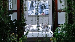 A bedroom with a bed, a large framed picture on the wall, and hanging plants. - Gili Pearl Villa (Gili Trawangan)