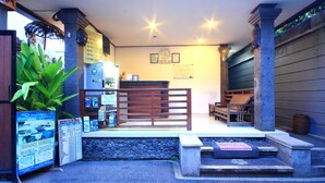 A reception area with a wooden desk, a clock, and a signboard. - Letos Kubu Homestay (Kuta)