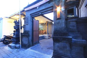 A traditional gate with a motorcycle parked nearby. - Letos Kubu Homestay (Kuta)
