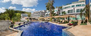 Una piscina rodeada de sillas de descanso y un edificio con varios balcones.