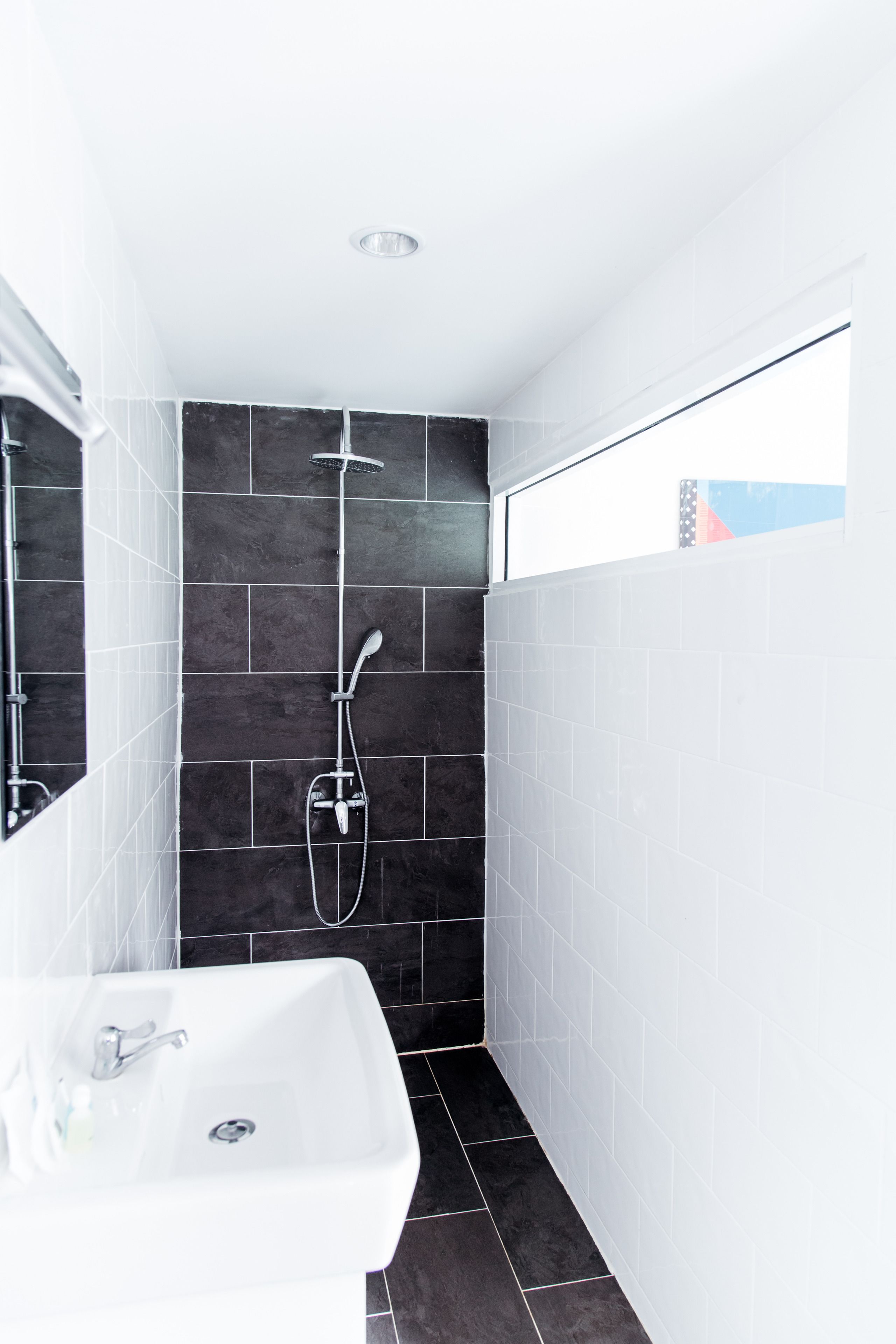Une salle de bain moderne avec une douche, un lavabo et un miroir.