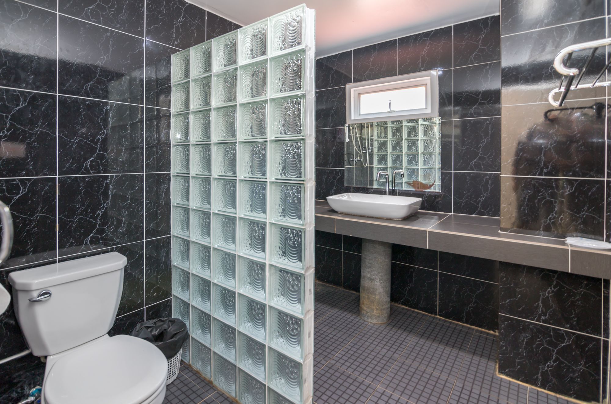 A modern bathroom with a toilet, a glass shower enclosure, and a sink with a mirror.