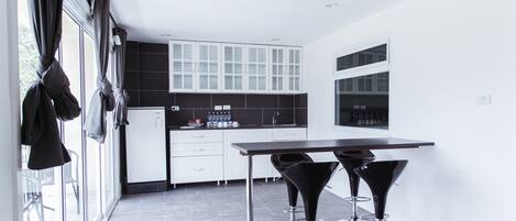 A modern kitchen with white cabinets, a black countertop, and two black bar stools.