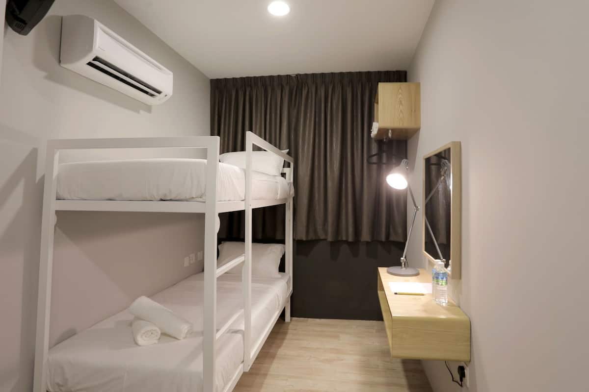 A bunk bed room with a desk, a lamp, and an air conditioner.