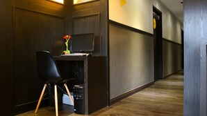 A reception desk with a computer, a black chair, and a vase with flowers. - Vio Hotel (Kuala Lumpur)