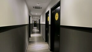 A long, narrow hallway with doors on both sides, each marked with a number. - Vio Hotel (Kuala Lumpur)