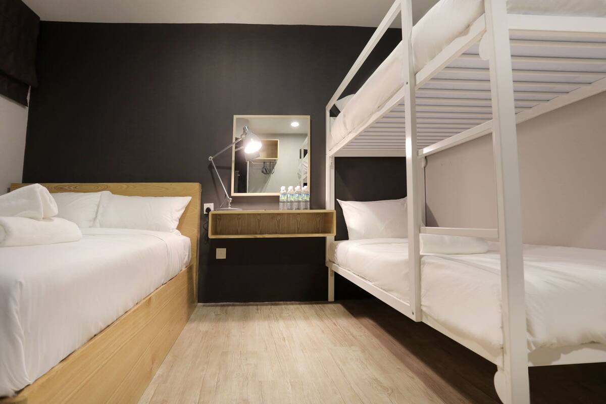 A bunk bed room with a wooden headboard, a bedside table with a lamp, and a mirror.