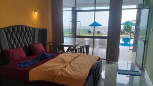 Quarto com cama, mesa e vista para a área da piscina.