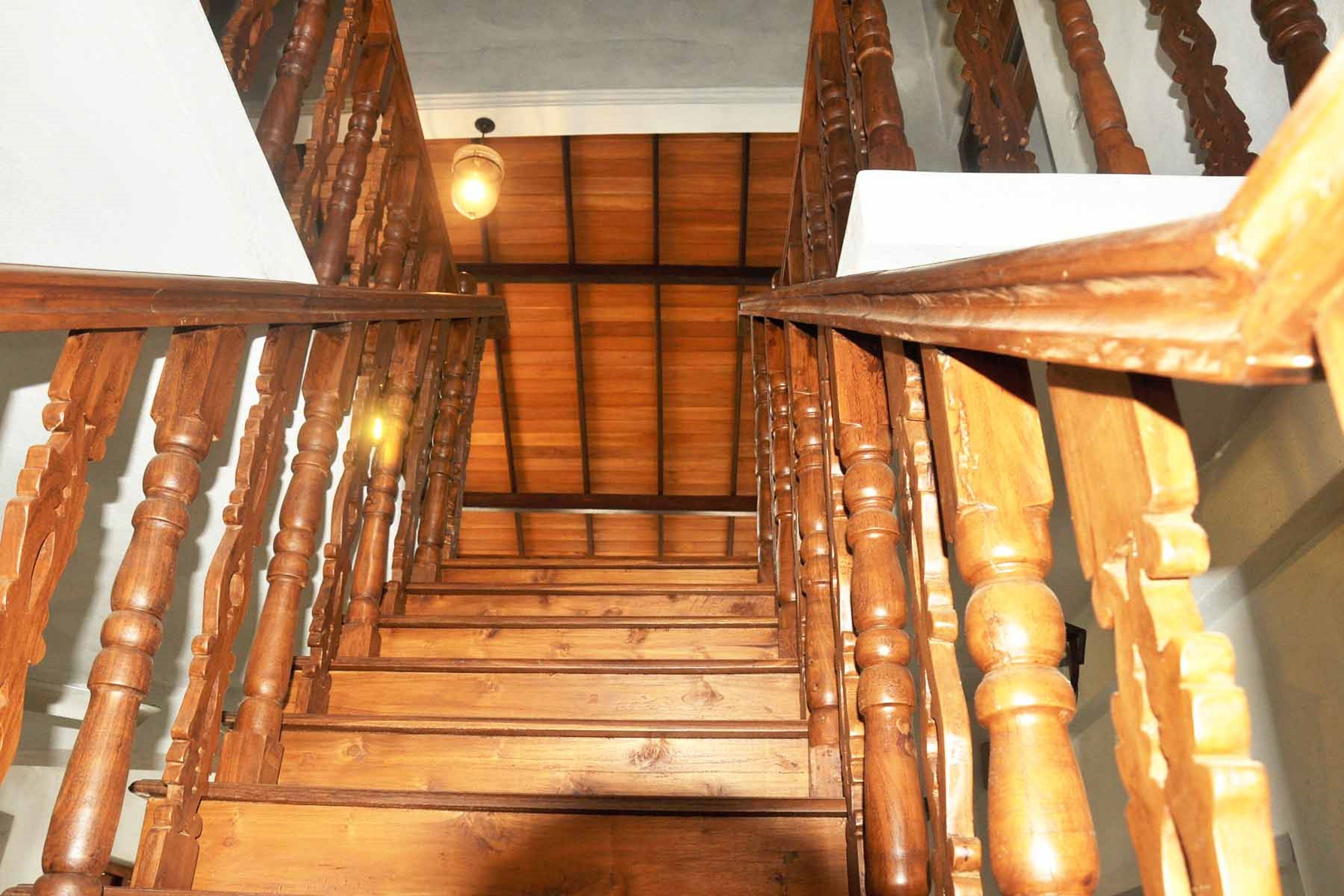 Un escalier en bois, doté d’une rampe et d’un luminaire en haut.