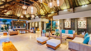 Un espacio interior amplio con mobiliario de madera, lámparas colgantes y paneles decorativos.
