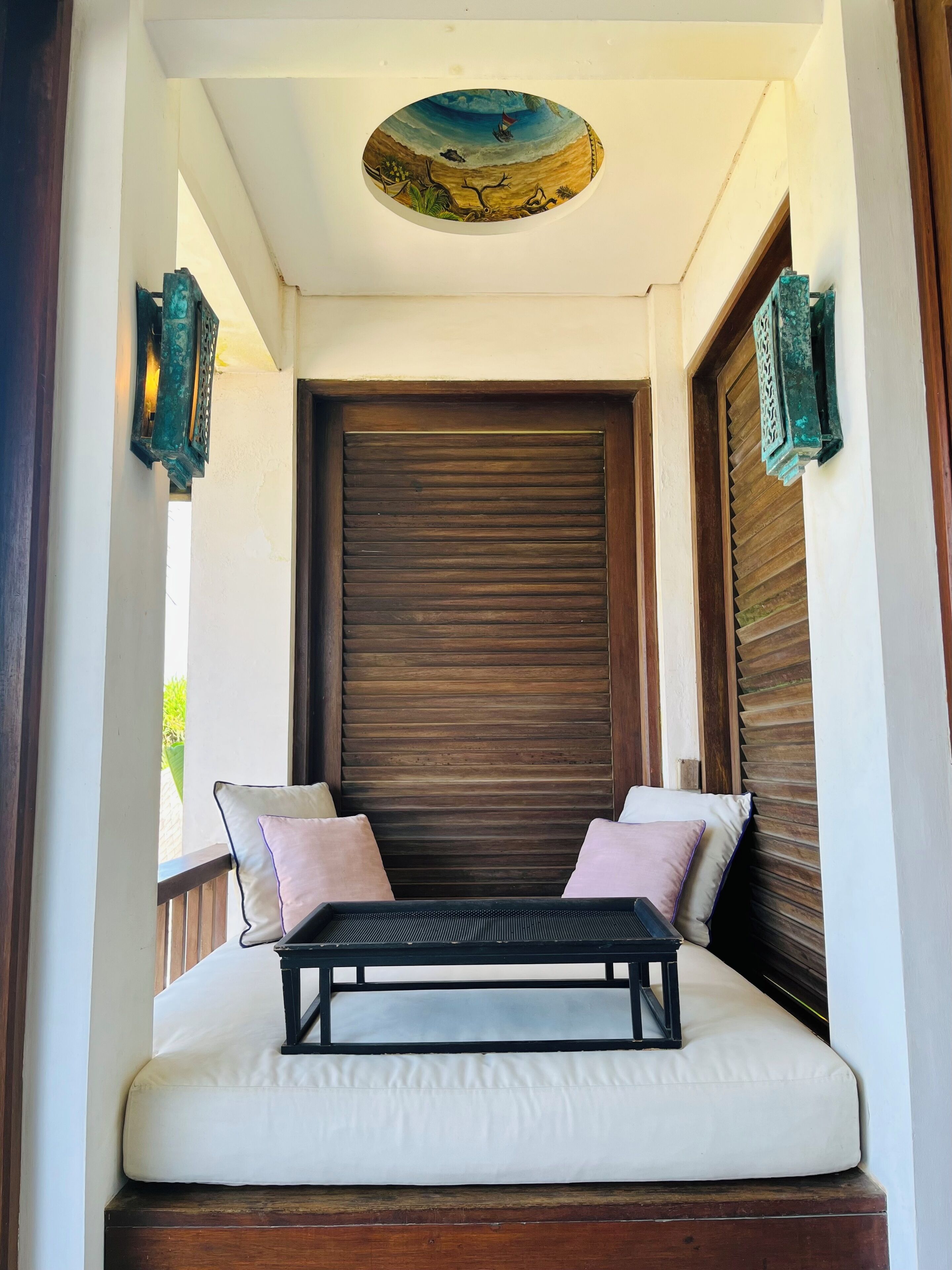 Ein Balkon mit gepolsterten Sitzgelegenheiten, einer Holzhakenschrankwand und einer dekorativen Decke.