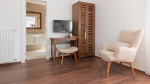 A room with a wooden floor, a desk with a chair, a television, a wardrobe, and a radiator. - Plitvice Miric Inn (Plitvicka Jezera)