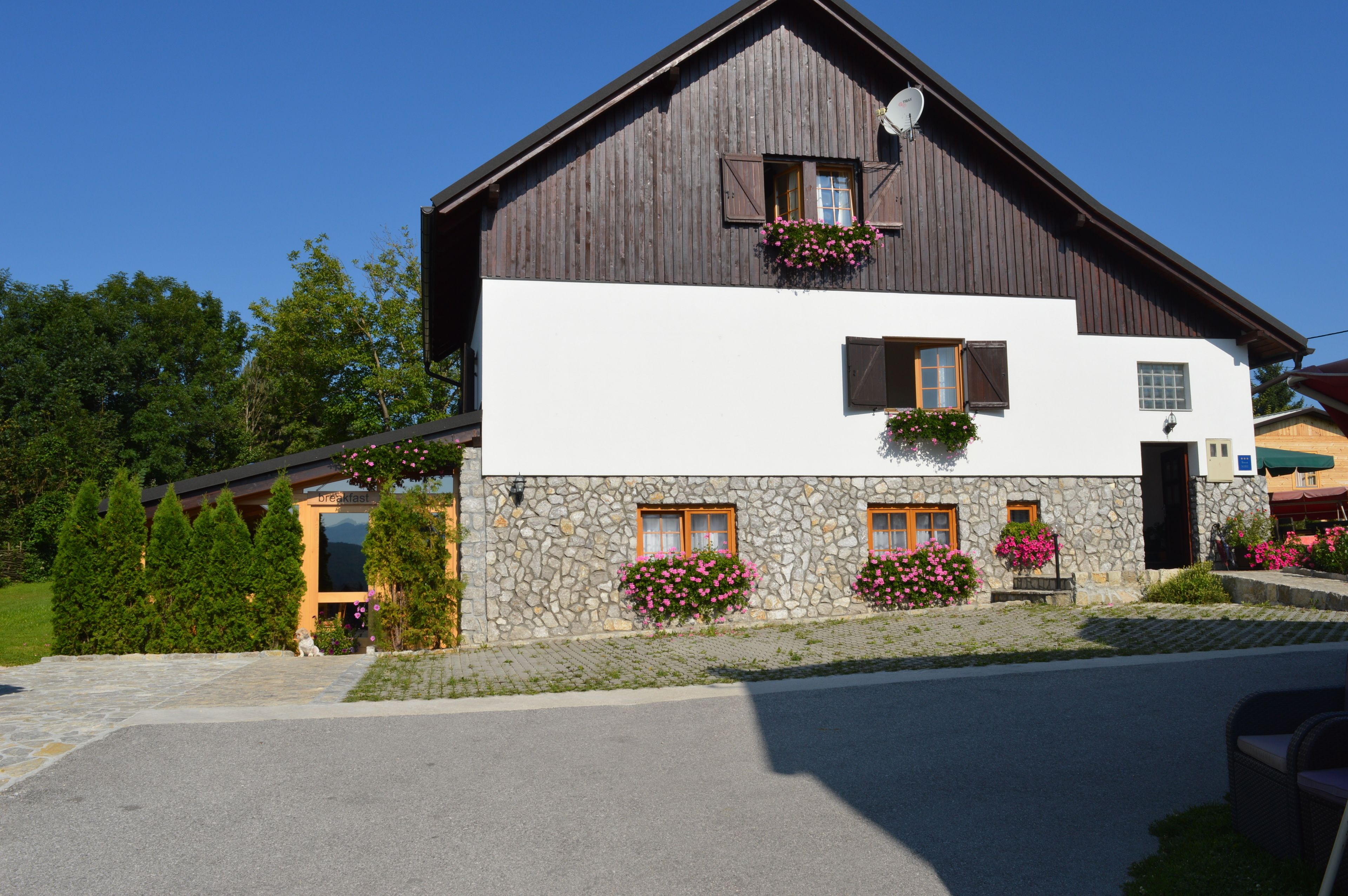 A two-story building with a stone facade, wooden upper section, and flower boxes on the windows.