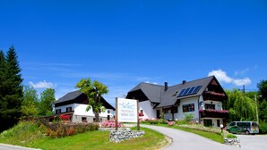 A hotel with a signboard, a pathway, and a parked van. - Plitvice Miric Inn (Plitvicka Jezera)
