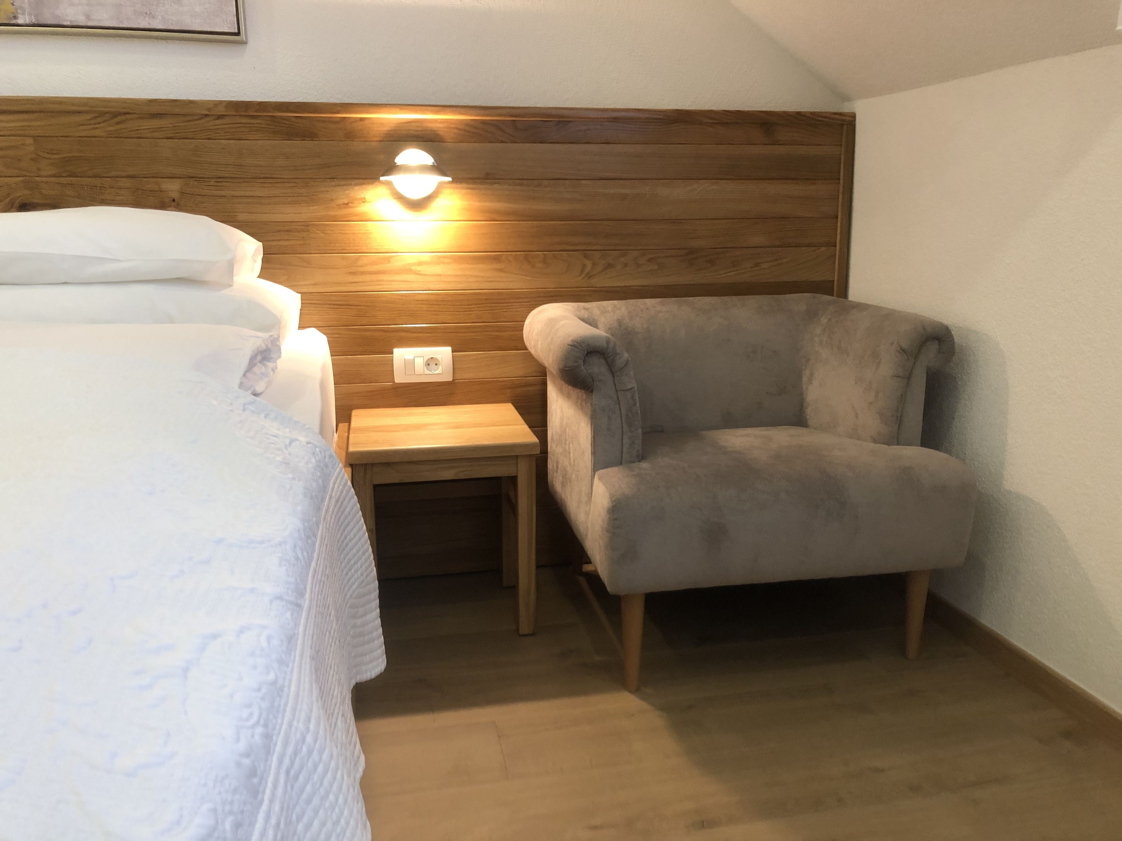 A bedroom with a bed, a nightstand, a lamp, and a chair.