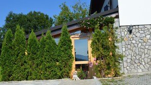 A building with a 'breakfast' sign, surrounded by trees and a stone wall.