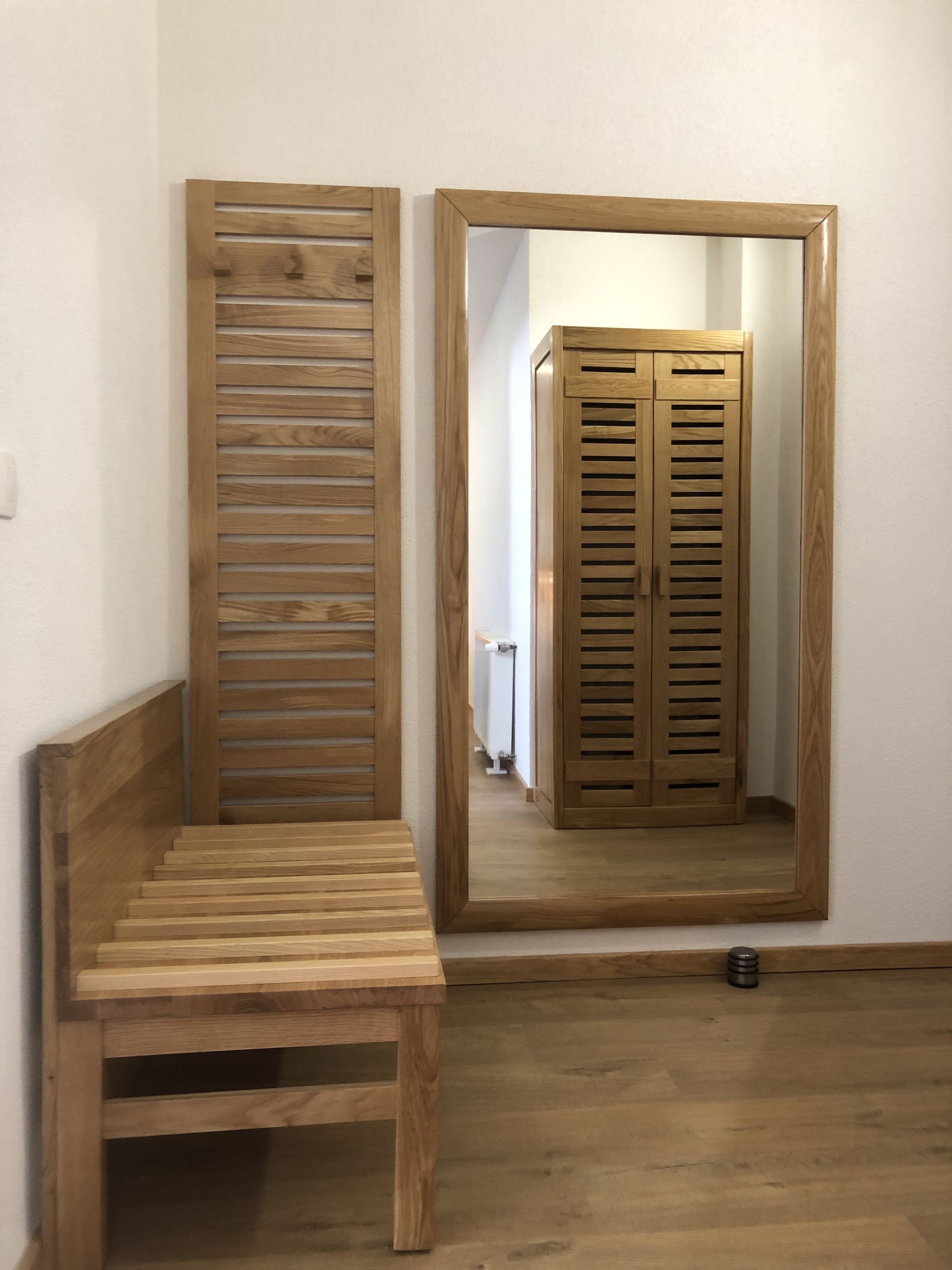 Un banco de madera y un espejo que refleja un armario de madera.